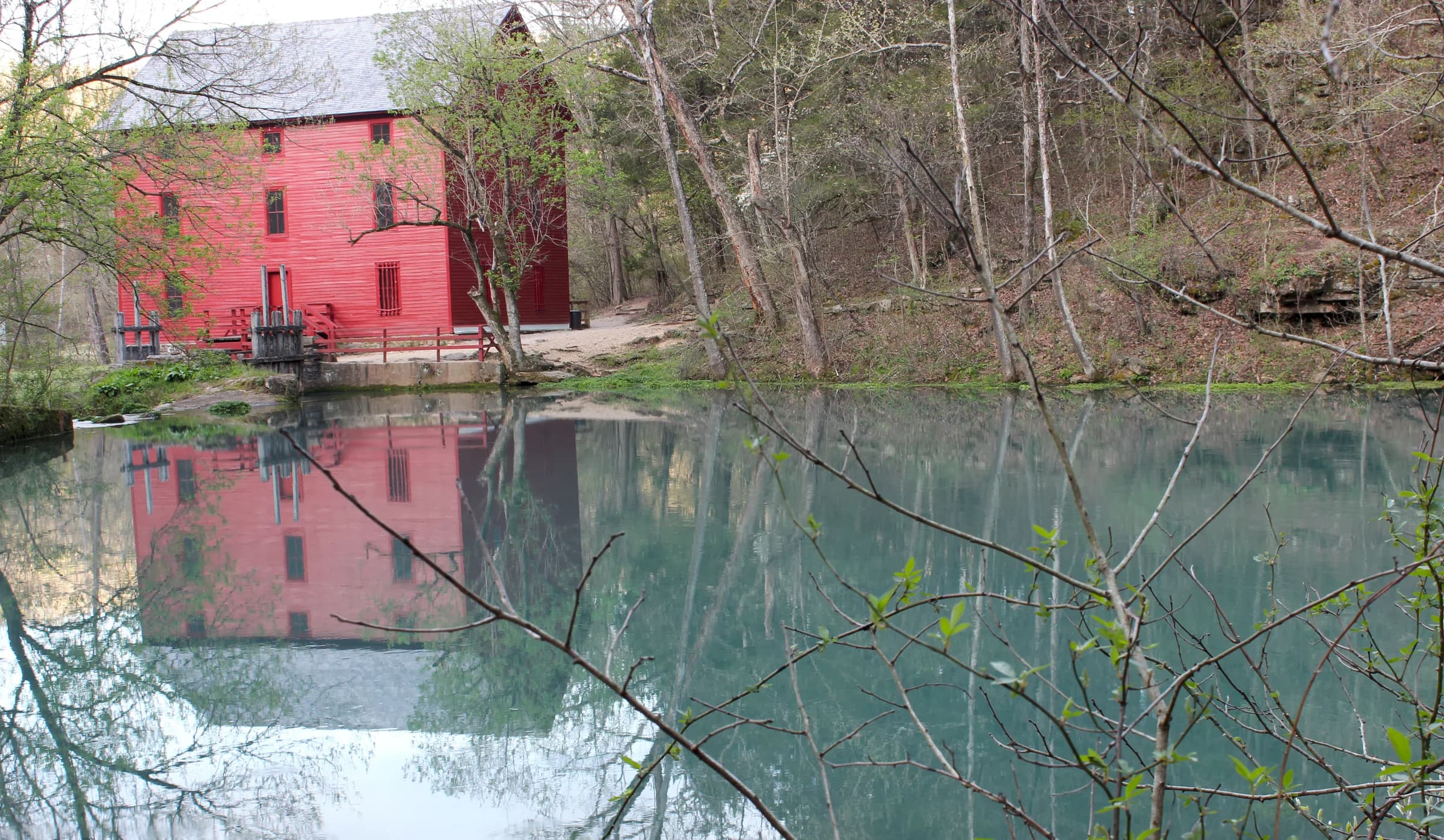The red Alley Spring mill reflected in the blue spring pool